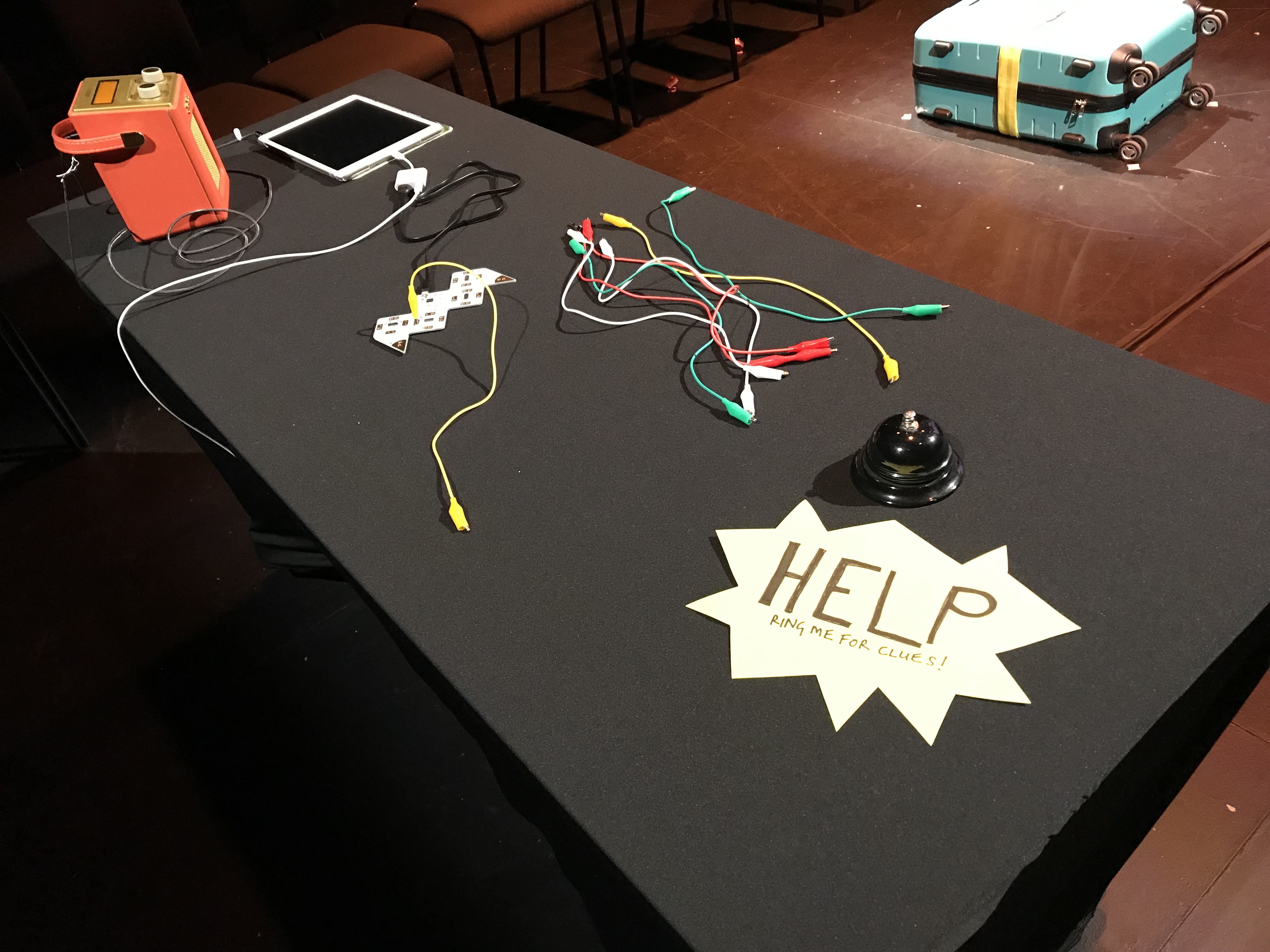 Desk with a playtron, some leads and a bell with a sign that says HELP