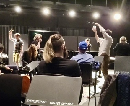 People in a workshop, a music stand in front says 'Birmingham Conservatoire'