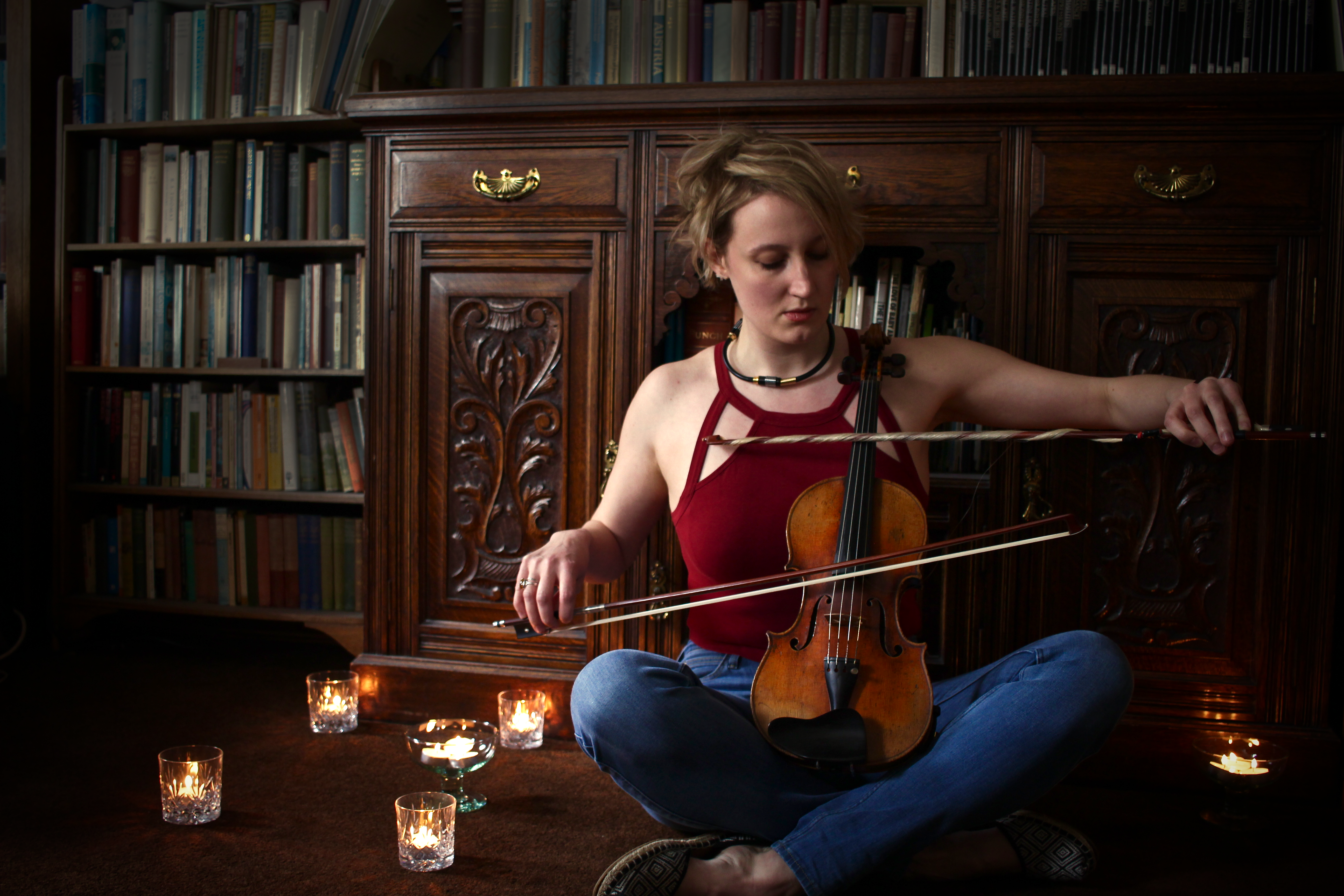 Emma Lloyd playing a violin resting on her lap with two bows